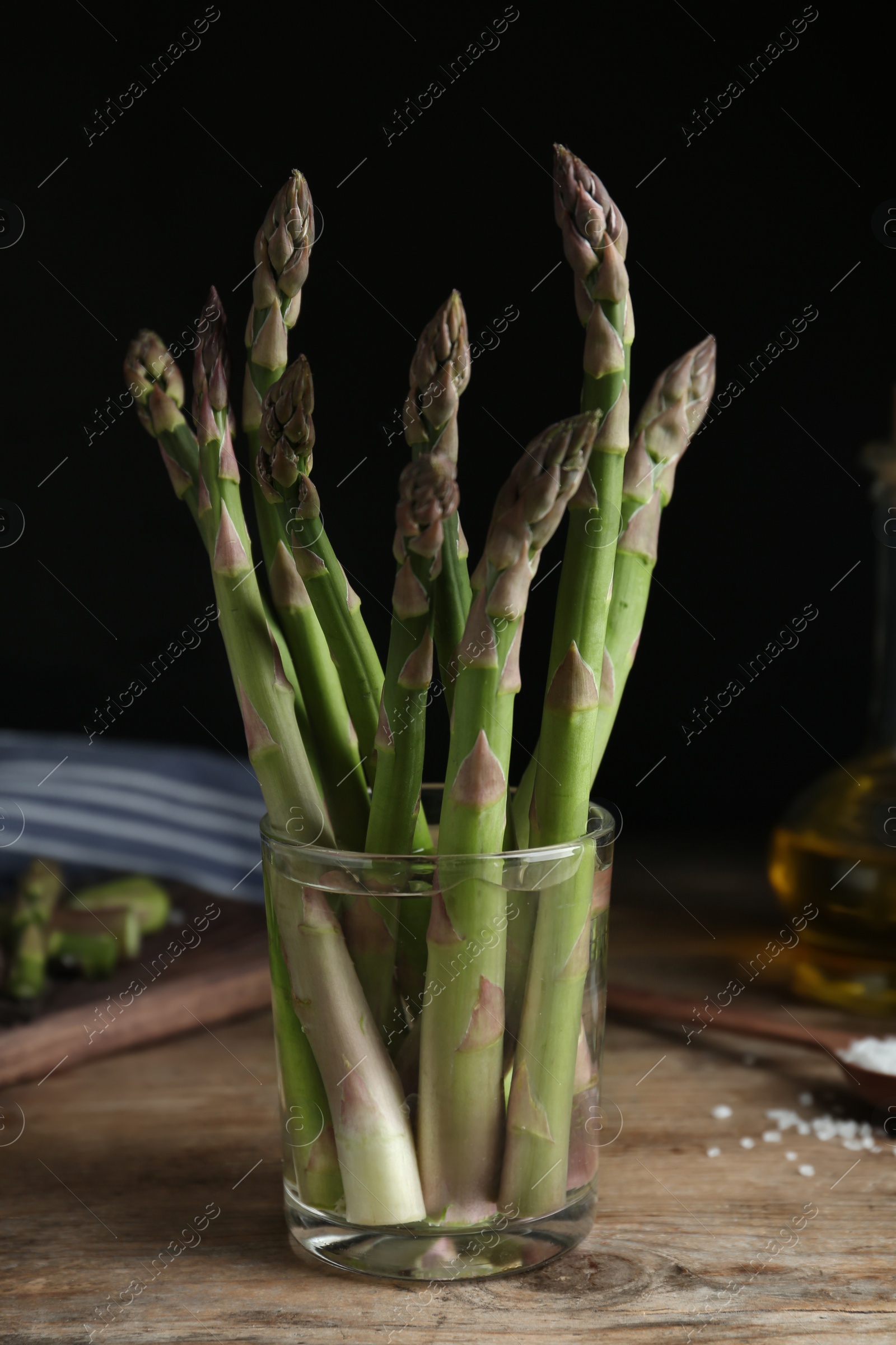 Photo of Fresh raw asparagus in glass on wooden table