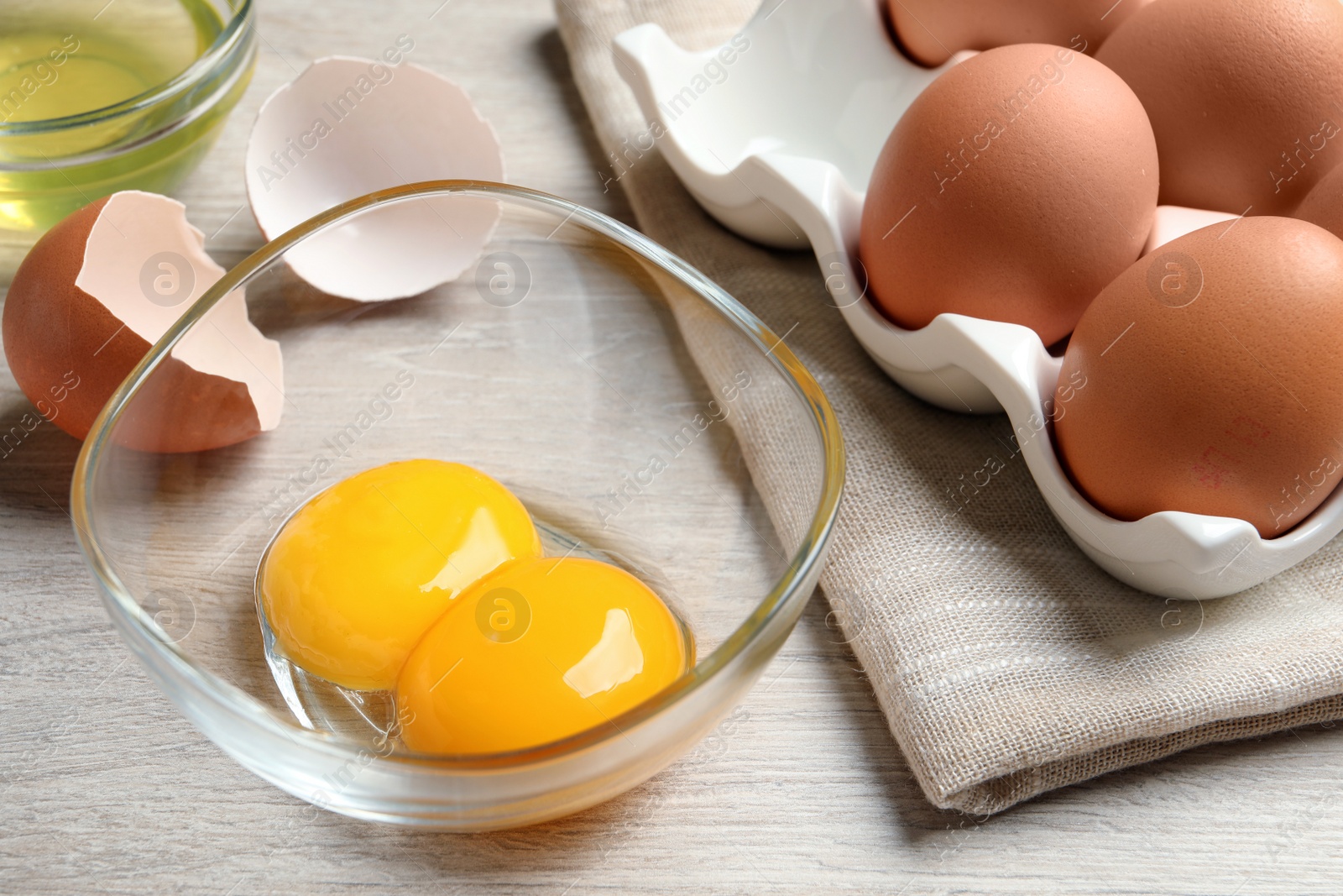 Photo of Raw chicken eggs and bowl with yolks on white wooden table