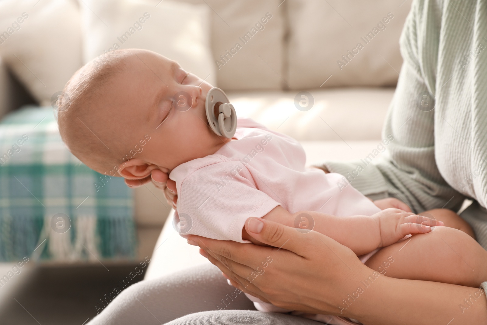 Photo of Mother holding her cute sleeping baby at home, closeup
