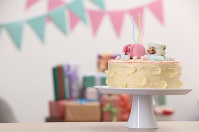 Photo of Delicious cake decorated with macarons and marshmallows on wooden table in festive room, space for text