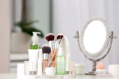 Photo of Cosmetic products and makeup accessories on table against blurred background