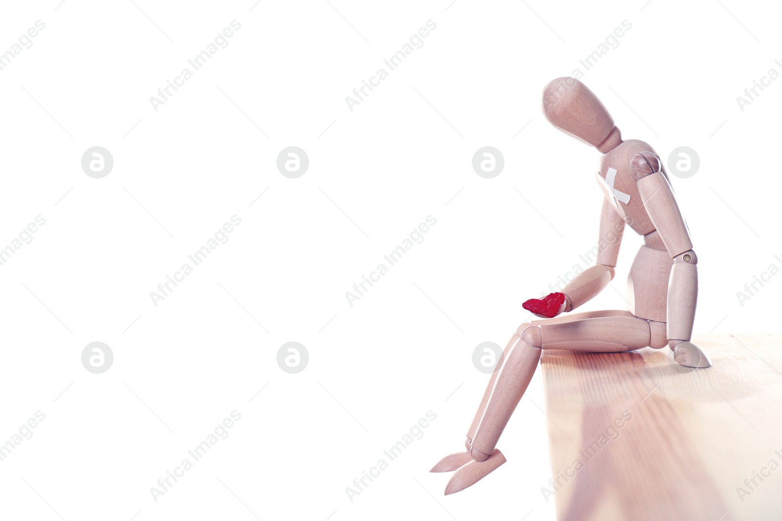 Image of Wooden puppet with small heart sitting on table against white background. Cheating concept