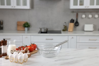 Whisk, bowl, and different ingredients on white marble table indoors, space for text