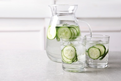 Glasses and jug of fresh cucumber water on table. Space for text