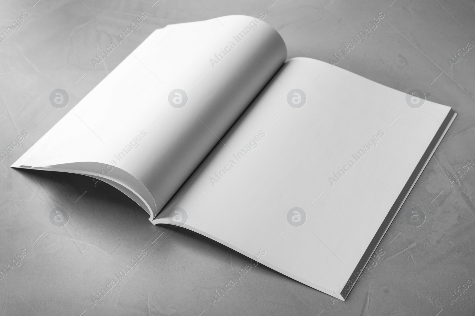 Photo of Blank open book on light grey stone background. Mock up for design