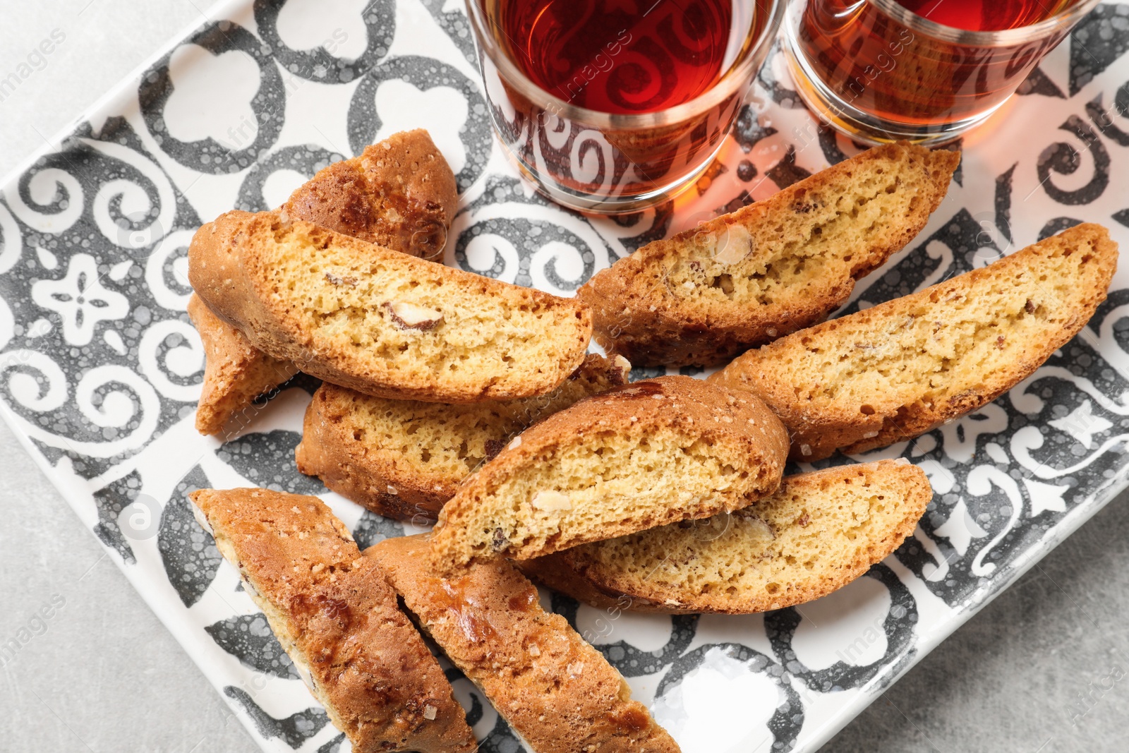 Photo of Tray with tasty cantucci and glasses of liqueur on light table, top view. Traditional Italian almond biscuits