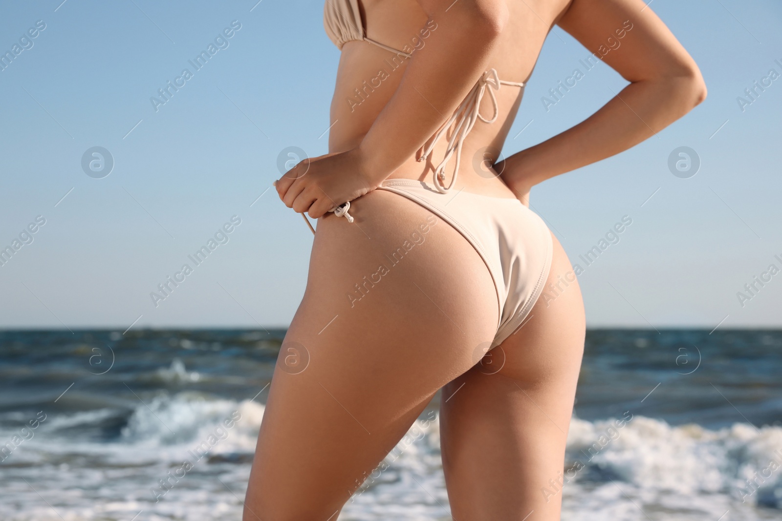 Photo of Young woman with attractive body on beach, closeup. Back view