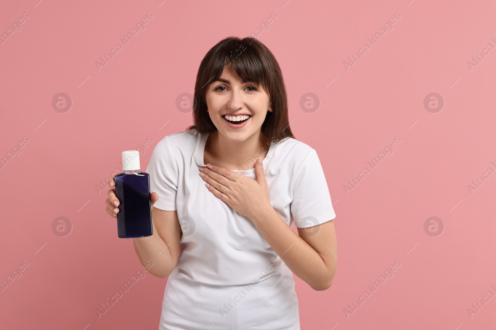 Photo of Young woman with mouthwash on pink background