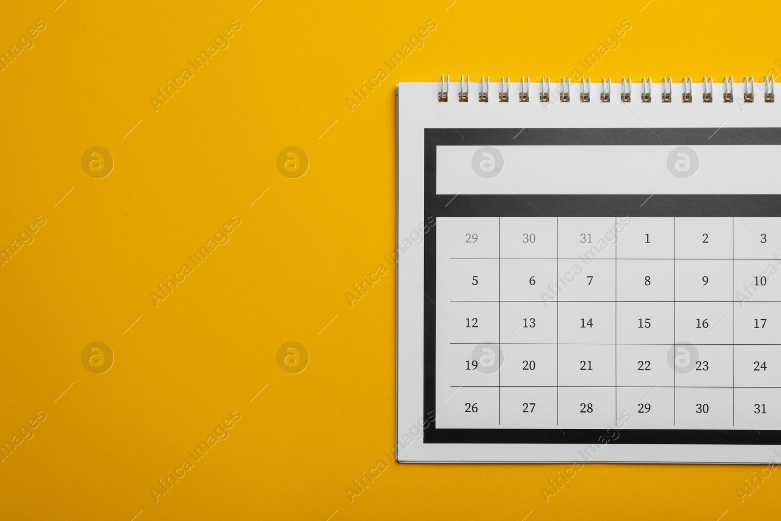 Photo of Paper calendar on yellow background, top view. Space for text