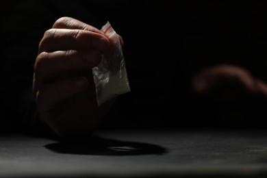 Photo of Addicted man with plastic bag of hard drug at grey table, closeup. Space for text