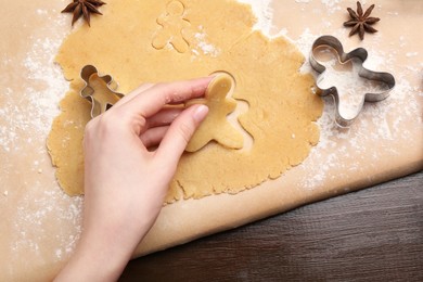 Photo of Woman making Christmas cookies with cutters at wooden table, top view