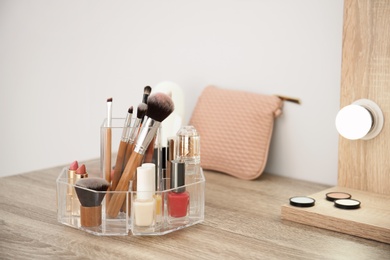 Photo of Makeup cosmetic products with tools in organizer on dressing table. Space for text