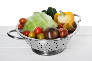 Photo of Metal colander with different vegetables on table against white background