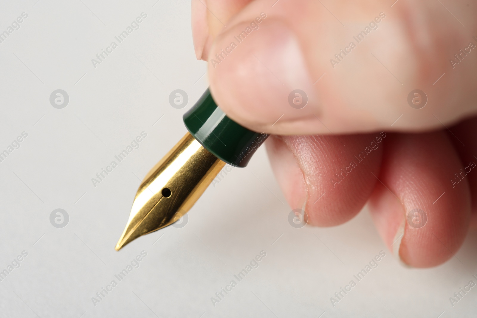 Photo of Woman with fountain pen above light paper, closeup