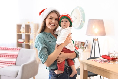 Young woman with baby in Christmas hats at home