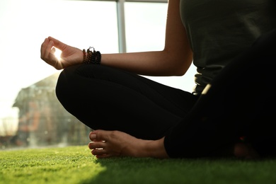 Photo of Young woman practicing yoga in sunlit room, closeup