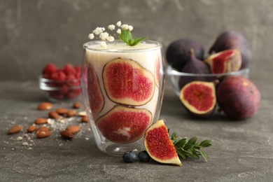 Delicious fig smoothie in glass on grey table