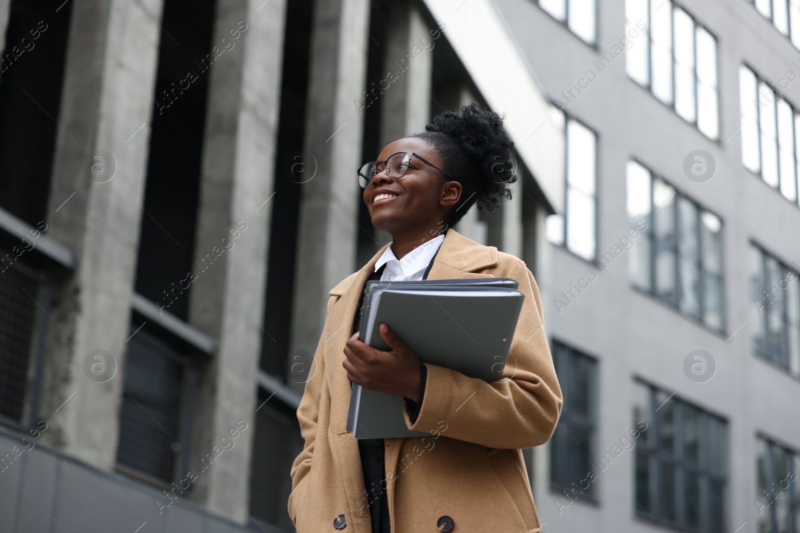 Photo of Happy woman with folders outdoors, low angle view. Lawyer, businesswoman, accountant or manager