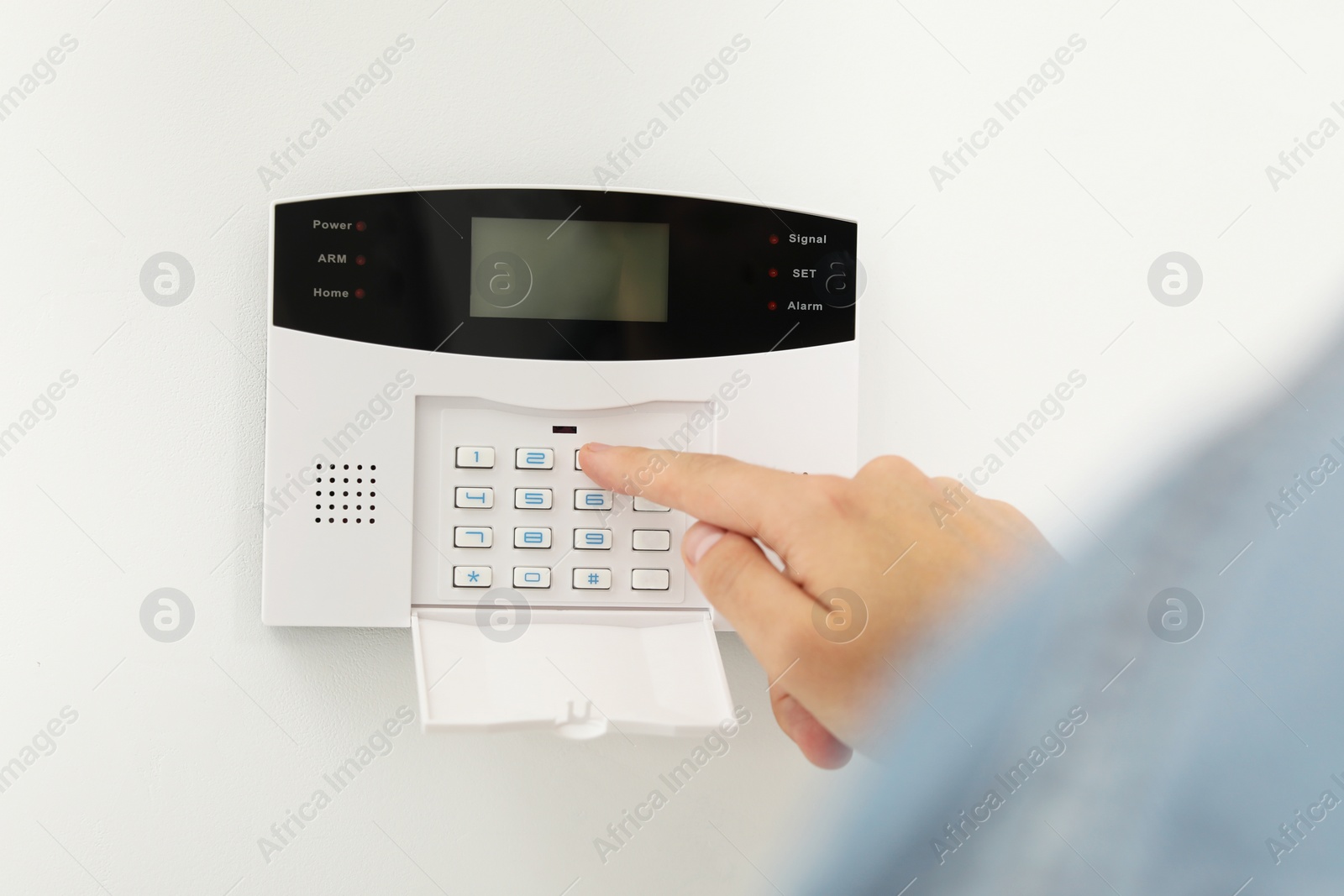 Photo of Man entering code on home security system indoors, closeup