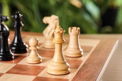 Photo of White wooden queen and other chess pieces on game board against blurred background