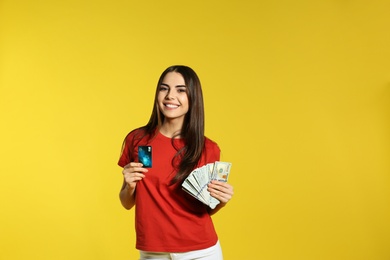 Photo of Young woman with money and credit card on color background. Space for text