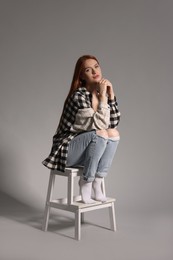 Photo of Beautiful young woman sitting on decorative ladder against gray background
