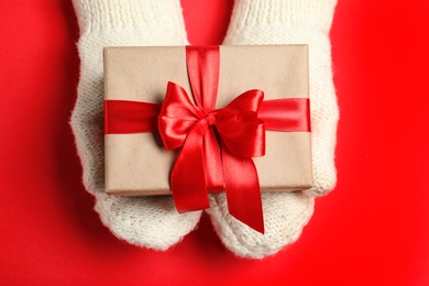 Photo of Woman holding Christmas gift on red table, top view