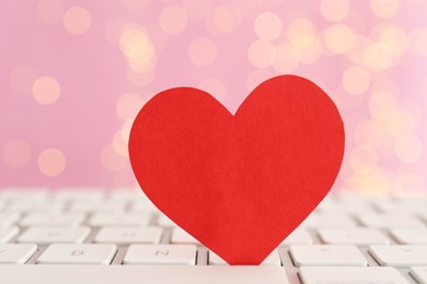 Red paper heart on computer keyboard, closeup. Online dating