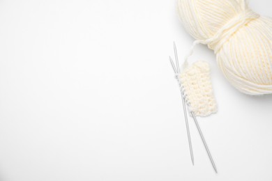 Photo of Soft woolen yarn, knitting and metal needles on white background, top view