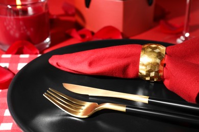 Photo of plate with cutlery and burning candle on red table for romantic dinner, closeup