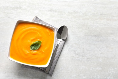 Flat lay composition with bowl of pumpkin soup and space for text on light background