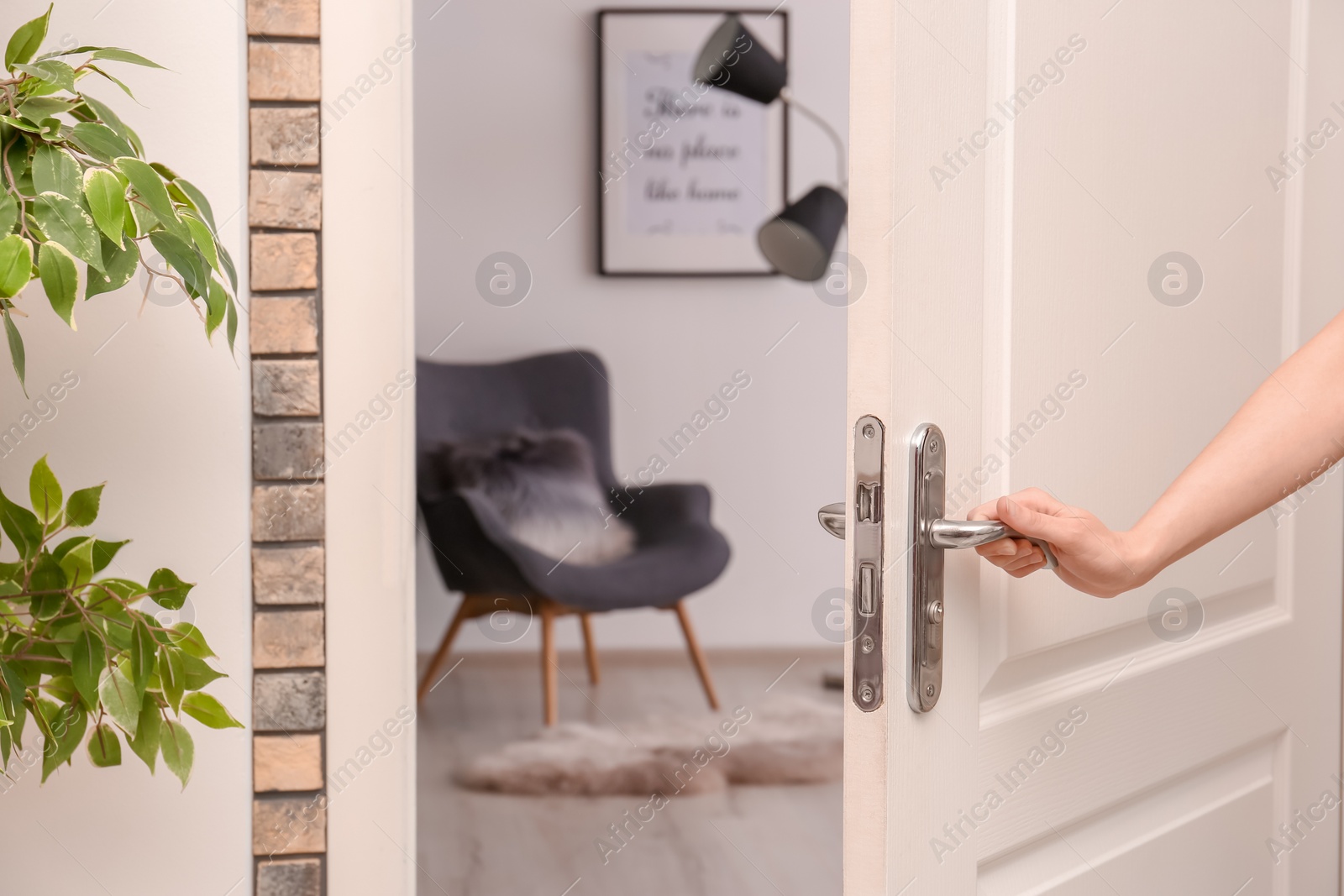 Photo of Young woman opening door to beautifully arranged room. Interior design