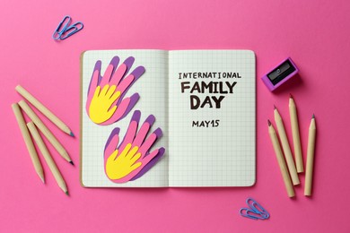 Photo of Notebook with text International Family Day May 15 and stationery on pink background, flat lay