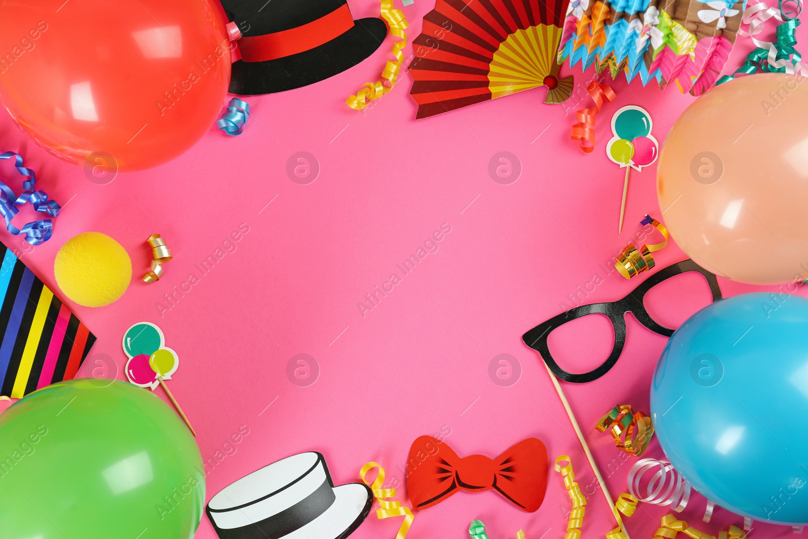 Photo of Frame of colorful serpentine streamers and other party accessories on pink background, flat lay. Space for text