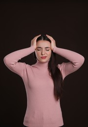 Photo of Young woman suffering from headache on dark background. Cold symptoms