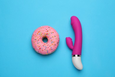 Photo of Pink vaginal vibrator and donut on light blue background, flat lay