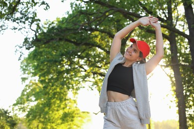 Photo of Young woman doing morning exercise in park. Space for text