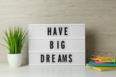 Photo of Lightbox with motivational quote Have Big Dreams, stationery and plant on white wooden table