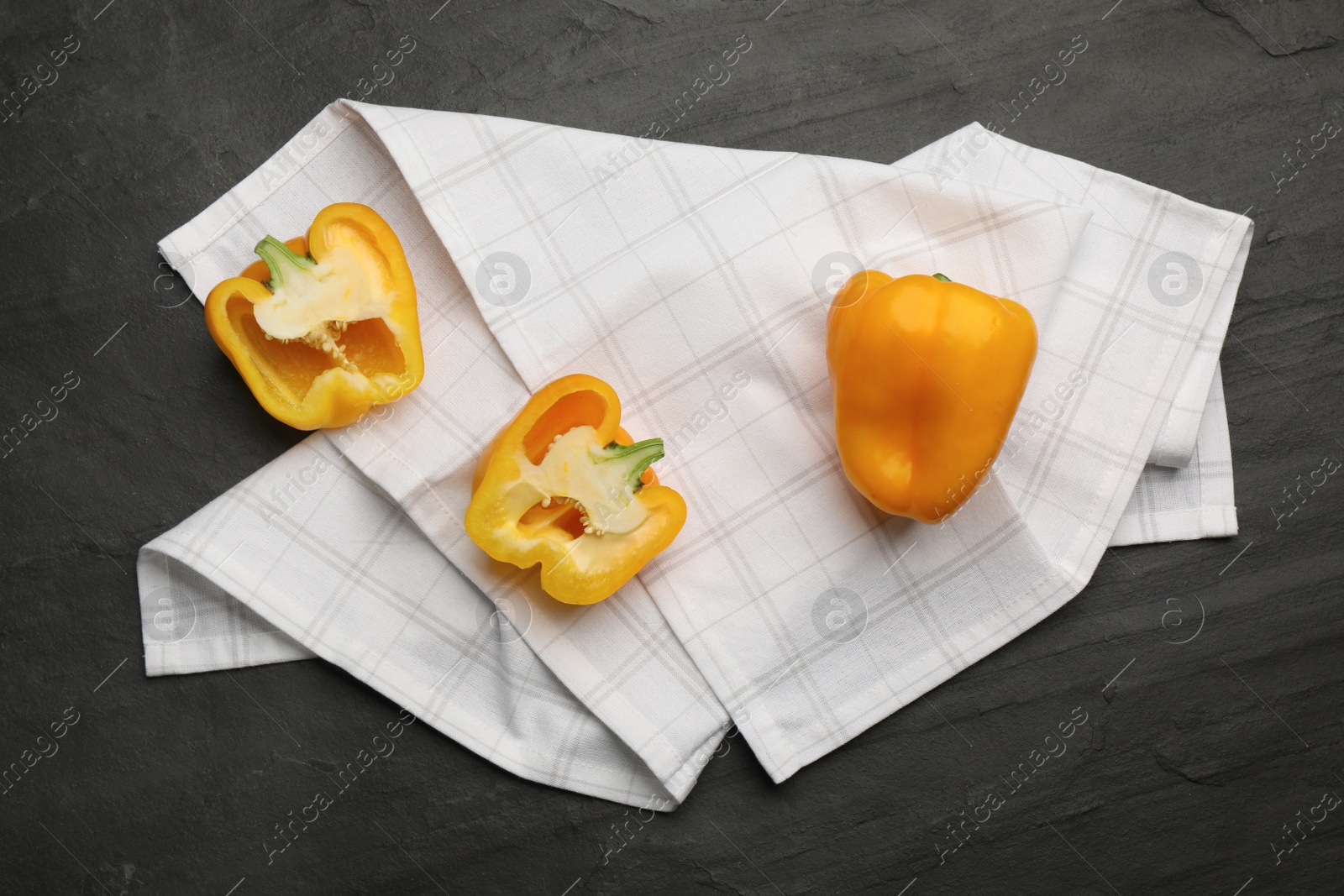 Photo of Kitchen towel with bell peppers on black table, flat lay