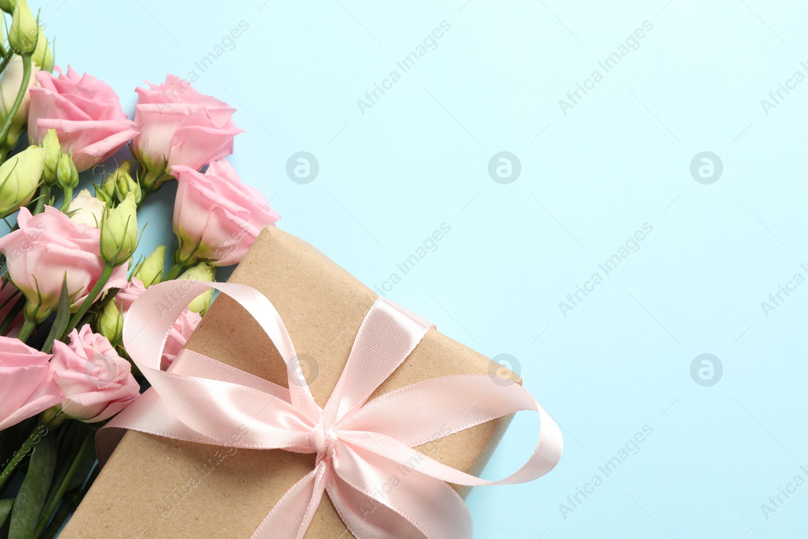 Photo of Happy Mother's Day. Beautiful flowers and gift box on light blue background, flat lay. Space for text