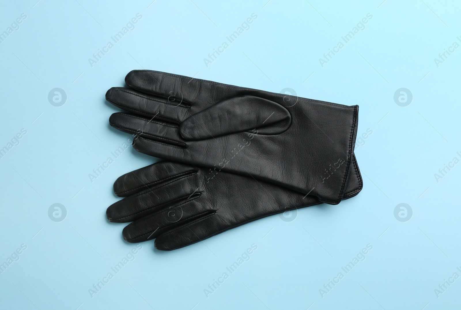 Photo of Pair of stylish leather gloves on light blue background, flat lay