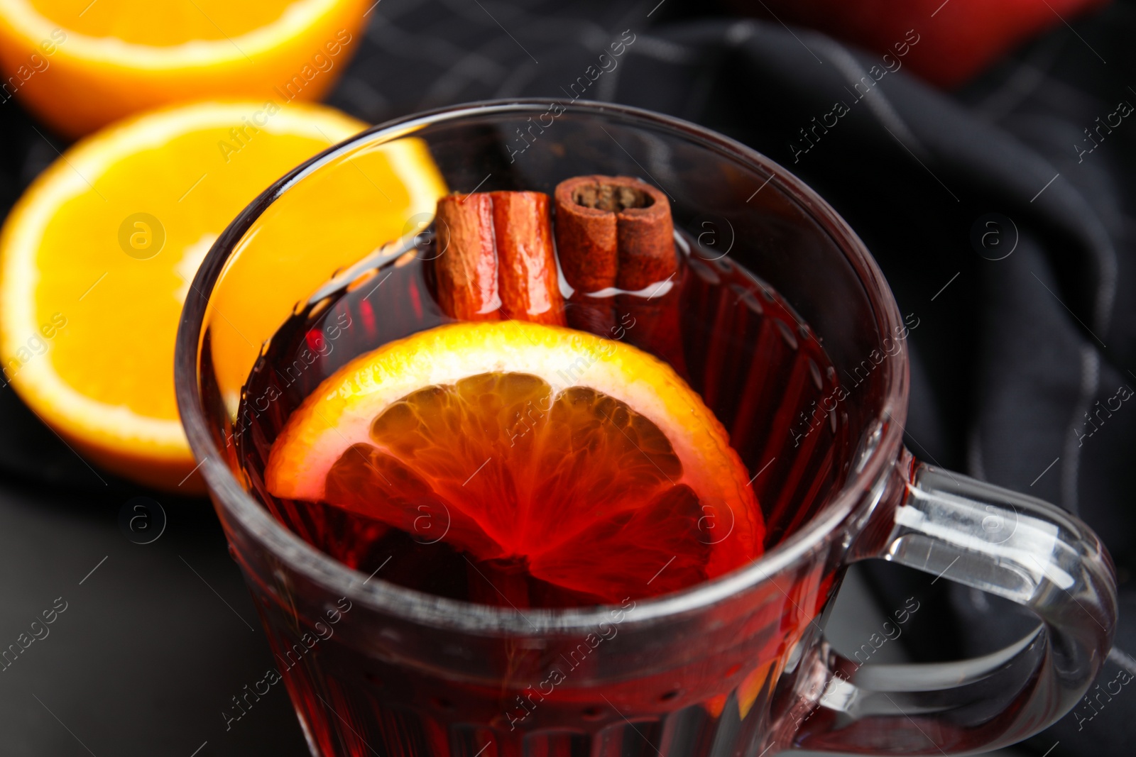 Photo of Glass cup of tasty mulled wine on black table, closeup