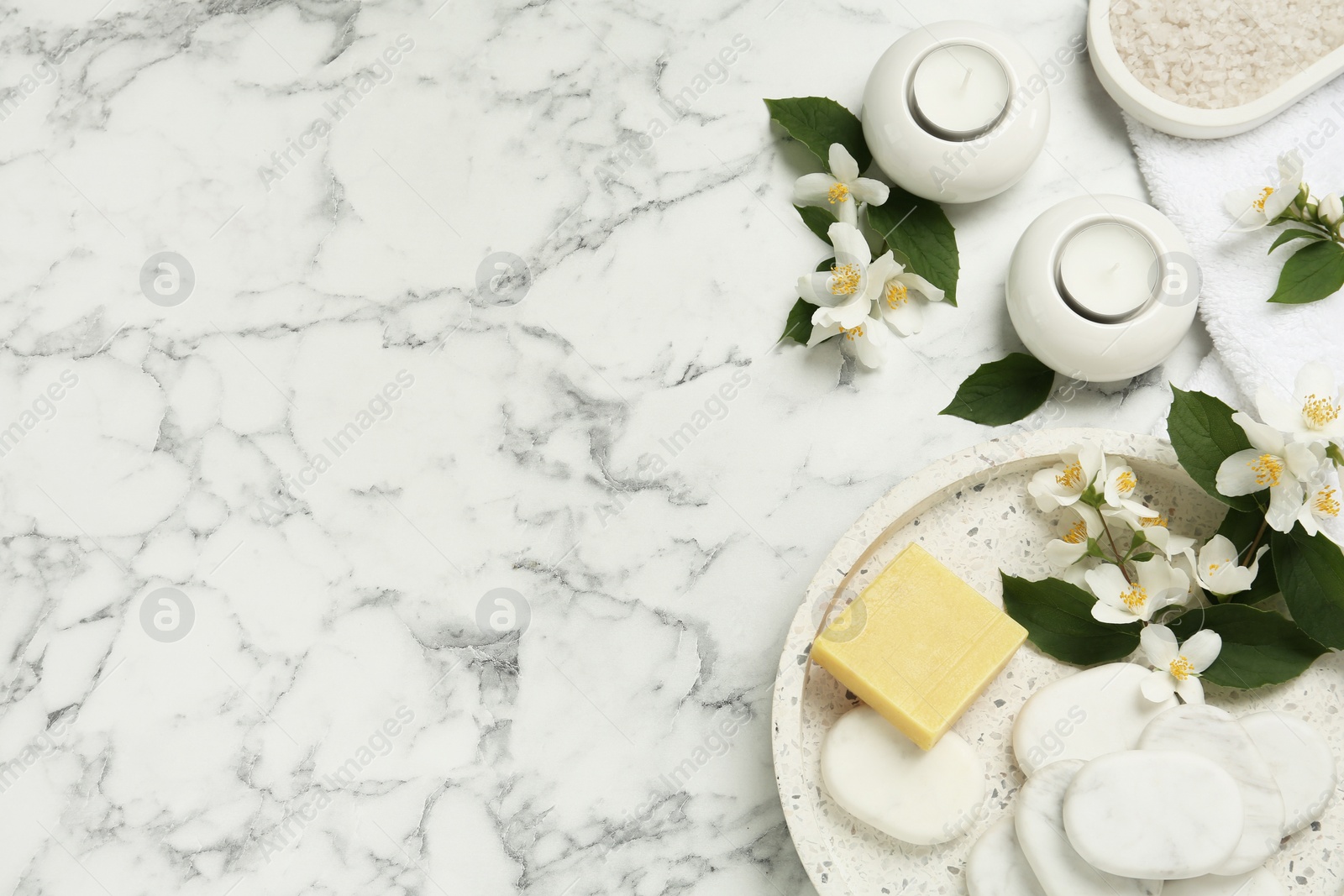 Photo of Flat lay composition with spa stones and beautiful jasmine flowers on white marble table, space for text