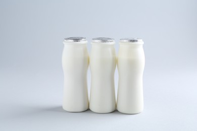 Photo of Tasty yogurt in bottles on light grey background