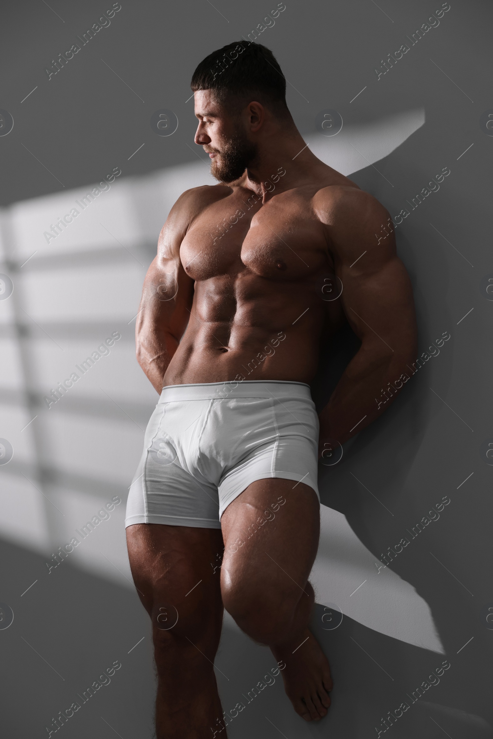 Photo of Young man in stylish white underwear near grey wall