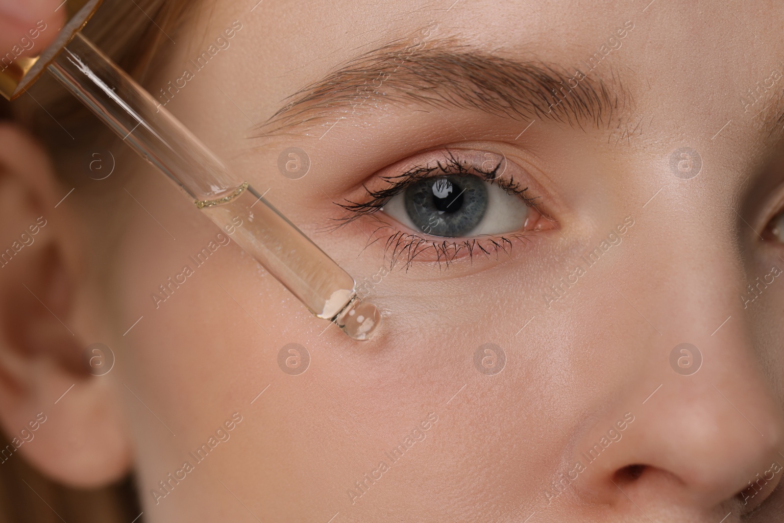 Photo of Woman applying essential oil onto face, closeup