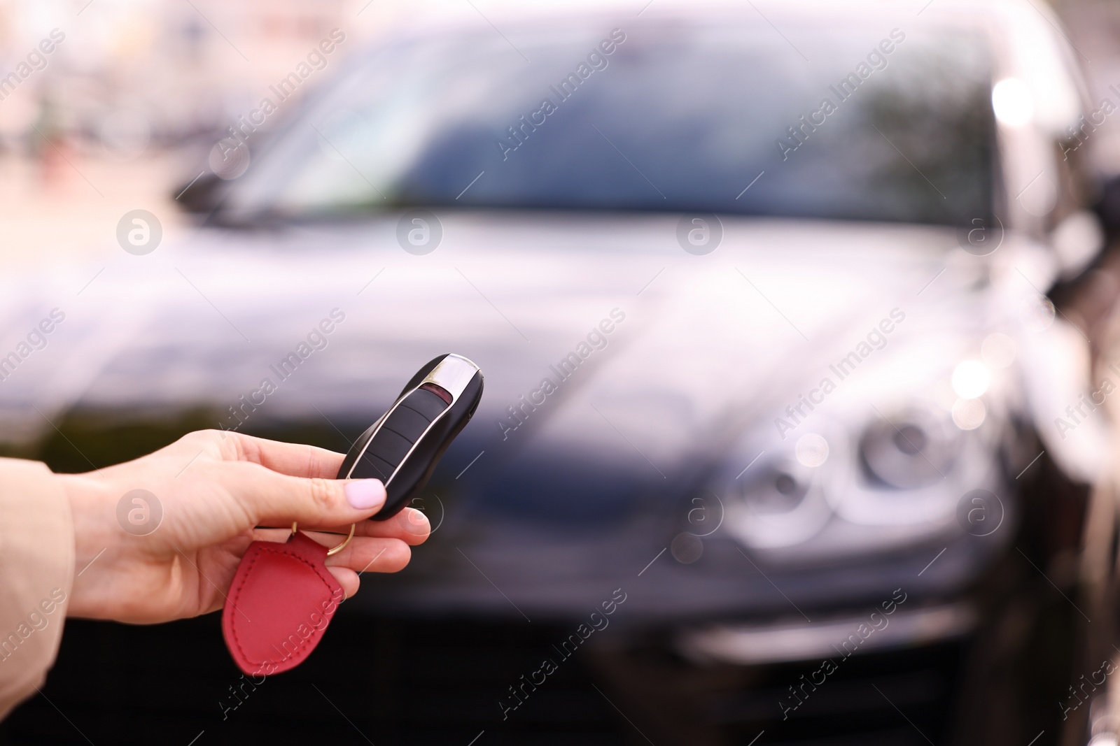 Photo of Woman holding car flip key near her vehicle outdoors, closeup