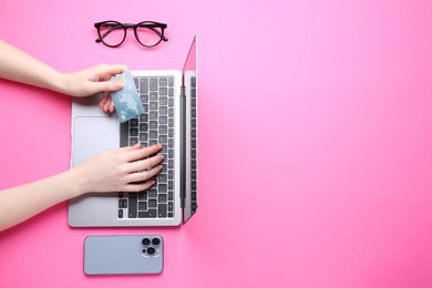 Photo of Online payment. Woman with laptop, smartphone and credit card on pink background, top view. Space for text