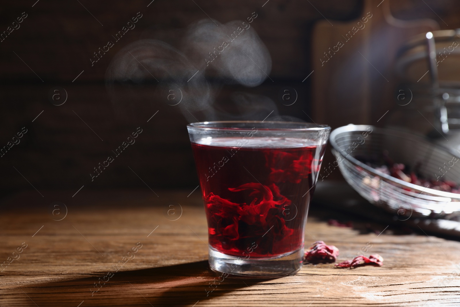 Photo of Delicious hibiscus tea in glass on wooden table, closeup