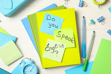 Photo of Question DO YOU SPEAK ENGLISH? and stationery on white wooden background, flat lay